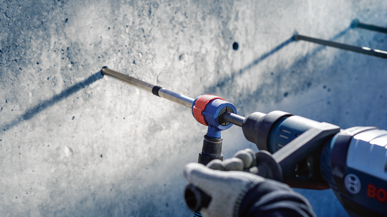 บุคคลที่สวมอุปกรณ์ความปลอดภัยกำลังเจาะเข้าไปในผนังคอนกรีต