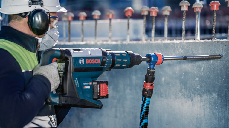 ชุดดอกสว่านเจาะกระแทก EXPERT SDS Clean plus-8X ขนาด 20 x 400 x 550 บุคคลที่สวมอุปกรณ์ความปลอดภัยกำลังเจาะเข้าไปในคอนกรีตด้วยค้อนโรตารี่