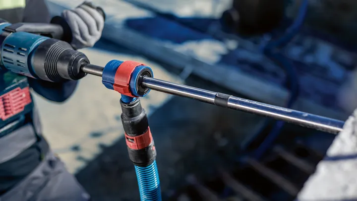 บุคคลที่สวมอุปกรณ์ความปลอดภัยใช้เครื่องมือโรตารีในการเจาะเข้าไปในคอนกรีต