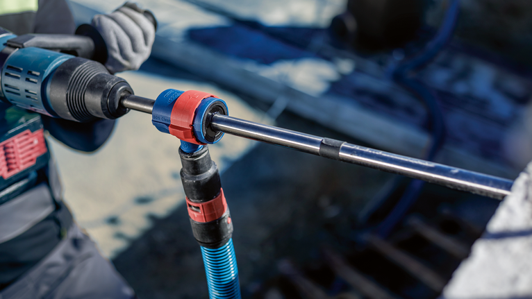 บุคคลที่สวมอุปกรณ์ความปลอดภัยใช้เครื่องมือโรตารีในการเจาะเข้าไปในคอนกรีต