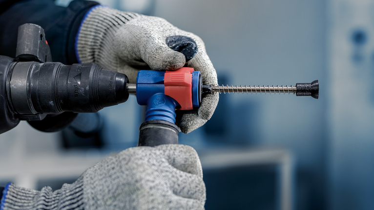 มือสวมถุงมือถือสว่านโรตารี่พร้อมดอกสกัด และสวมอุปกรณ์ป้องกันความปลอดภัย.