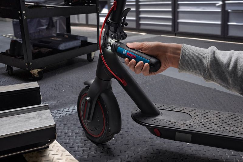 คนใช้ไขควงไร้สายเพื่อปรับแฮนด์ของสกู๊ตเตอร์ไฟฟ้า.