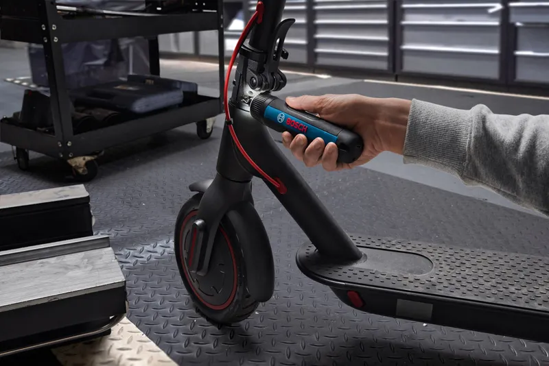 คนใช้ไขควงไร้สายเพื่อปรับแฮนด์ของสกู๊ตเตอร์ไฟฟ้า.