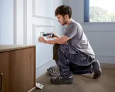 คนใช้ไขควงไร้สายในการติดตั้งฝาครอบเต้ารับไฟฟ้า.