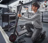 คนกำลังซ่อมสกู๊ตเตอร์ไฟฟ้าโดยใช้ไขควงไร้สายในโรงงาน.