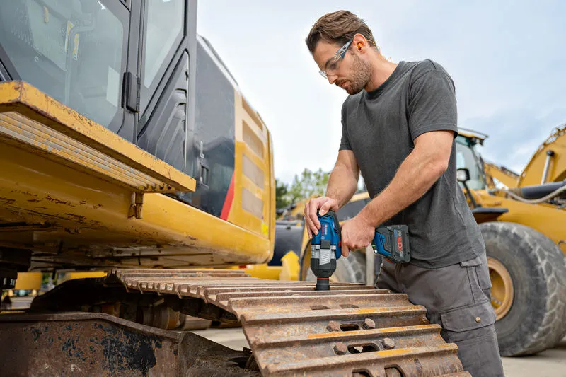 บุคคลที่สวมอุปกรณ์ด้านความปลอดภัยใช้ประแจกระแทกไร้สายบนรางขุด.