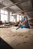 เครื่องเป่าลม Bosch GBL 650 กำลังช่วยขจัดขี้เลื่อยจากโต๊ะทำงาน.