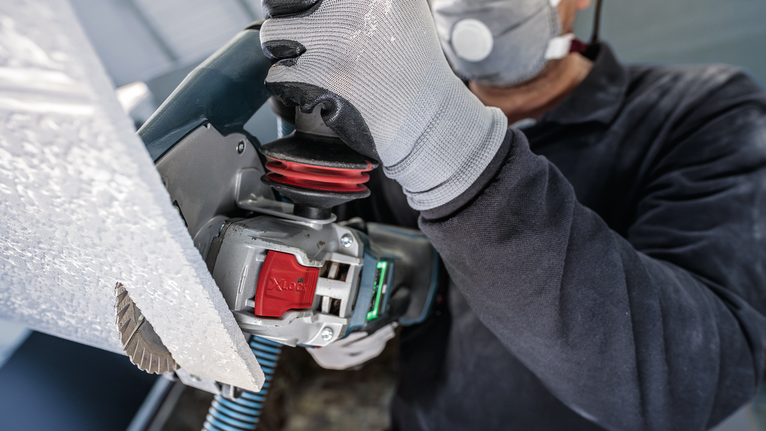 บุคคลที่สวมอุปกรณ์ความปลอดภัยกำลังตัดแผงด้วยเครื่องมือไฟฟ้า