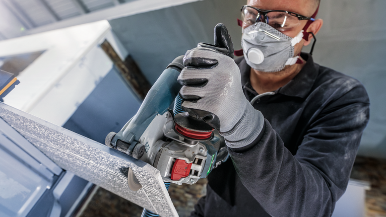 บุคคลที่สวมอุปกรณ์ความปลอดภัยตัดแผงโลหะด้วยเครื่องมือไฟฟ้า