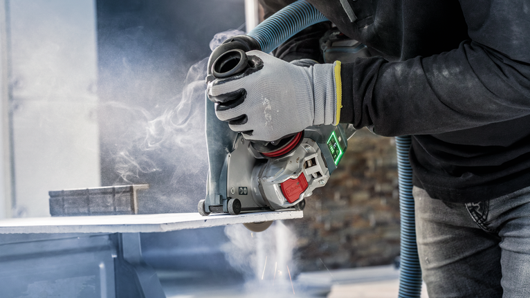 ผู้ที่สวมอุปกรณ์ความปลอดภัยใช้เครื่องตัดไฟฟ้าตัดแผ่นหิน