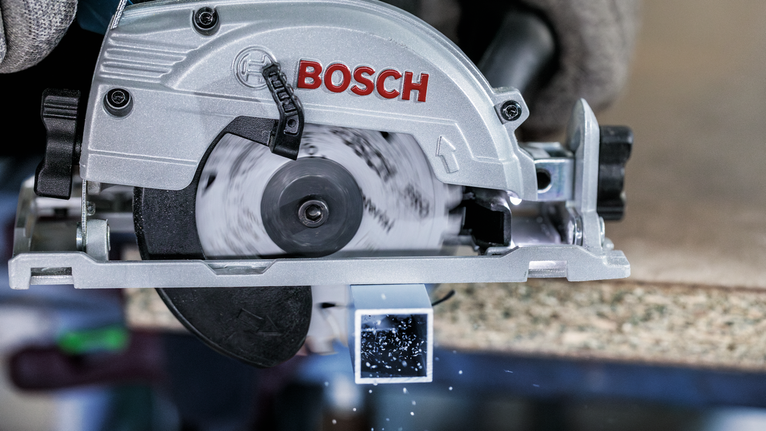 บุคคลที่สวมอุปกรณ์ความปลอดภัยใช้เลื่อยวงเดือนตัดท่อโลหะสี่เหลี่ยม