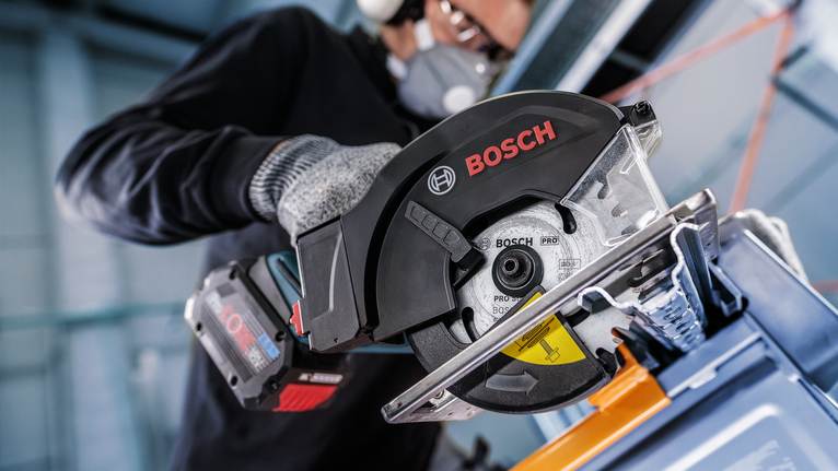 บุคคลที่สวมอุปกรณ์ความปลอดภัยใช้เลื่อยวงเดือนตัดโลหะ