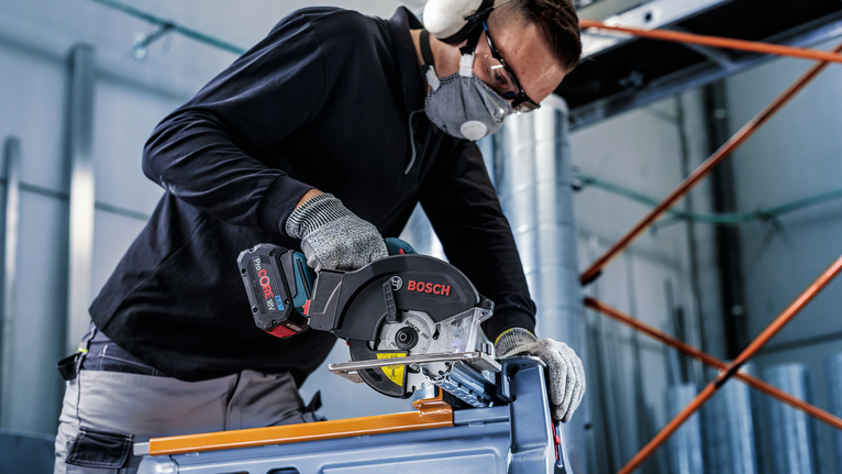 บุคคลที่สวมอุปกรณ์ความปลอดภัยใช้เลื่อยวงเดือนตัดโลหะ