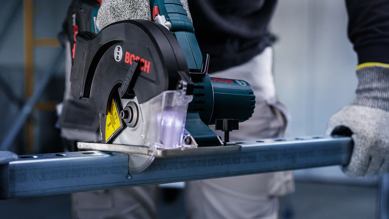 บุคคลที่สวมอุปกรณ์ความปลอดภัยกำลังตัดโลหะด้วยเลื่อยวงเดือน