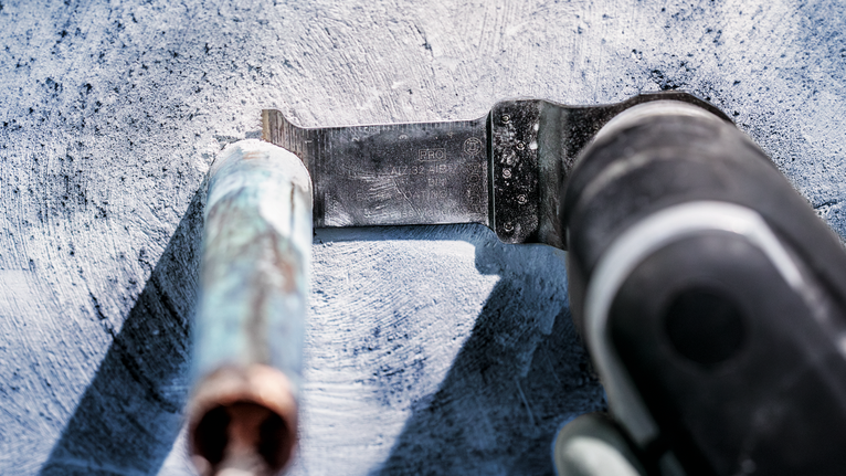 เครื่องมือสั่นตัดผ่านท่อโลหะบนพื้นคอนกรีต