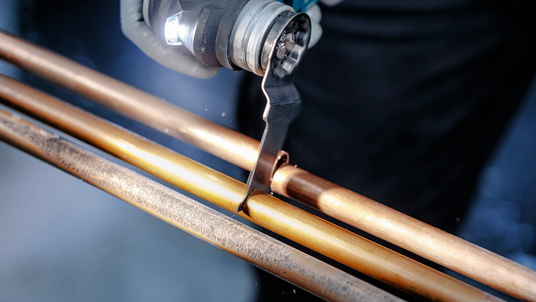 คนกำลังใช้เครื่องมือสั่นเพื่อตัดท่อทองแดง