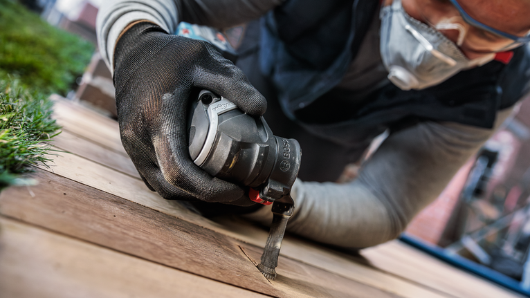 บุคคลที่สวมอุปกรณ์ความปลอดภัยใช้เครื่องมือไฟฟ้าตัดไม้กระดาน