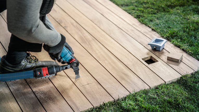 บุคคลที่สวมอุปกรณ์ความปลอดภัยกำลังตัดพื้นไม้ด้วยเครื่องมือไฟฟ้า