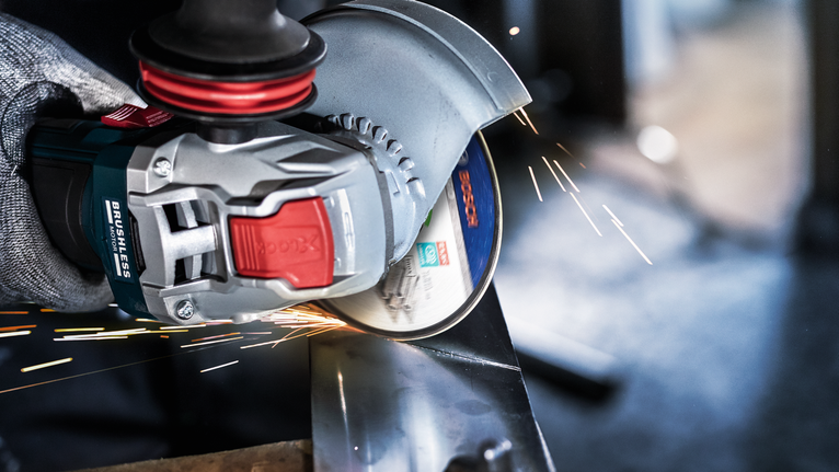 บุคคลที่สวมอุปกรณ์ความปลอดภัยกำลังบดโลหะ ทำให้เกิดประกายไฟที่สว่าง