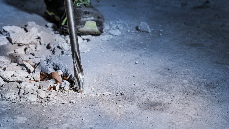 การเจาะด้วยค้อนโรตารี่ลงในพื้นคอนกรีตใกล้กับเศษซากที่กระจัดกระจาย