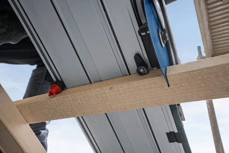 ใบเลื่อยวงเดือนตัดผ่านคานไม้ในไซต์ก่อสร้าง.