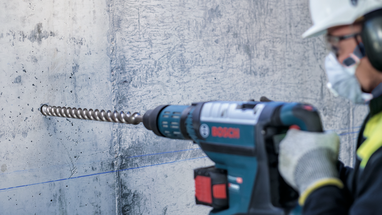 ผู้ที่สวมอุปกรณ์ความปลอดภัยกำลังเจาะเข้าไปในผนังคอนกรีต