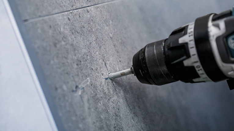 สว่านเจาะรูที่แม่นยำบนผนังกระเบื้องสีเทา