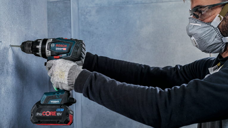 ผู้ที่สวมอุปกรณ์ความปลอดภัยกำลังเจาะเข้าไปในผนังคอนกรีต