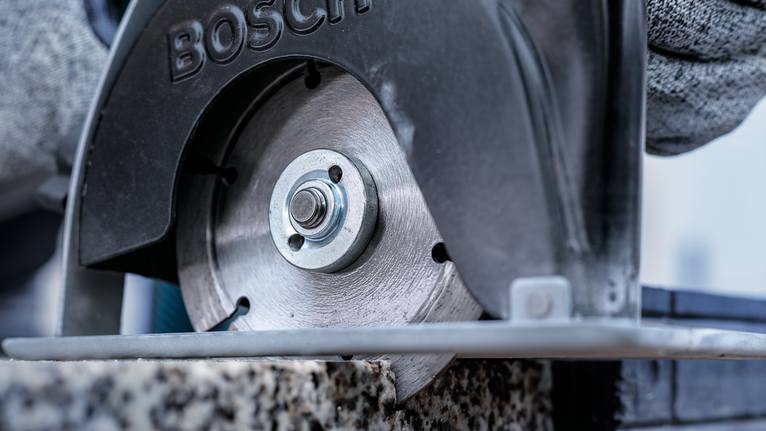 บุคคลที่สวมอุปกรณ์ความปลอดภัยกำลังตัดหินด้วยเลื่อยวงเดือน