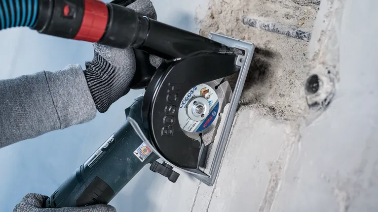 บุคคลที่สวมอุปกรณ์ด้านความปลอดภัยใช้เครื่องไล่ผนังเพื่อตัดช่องในคอนกรีต