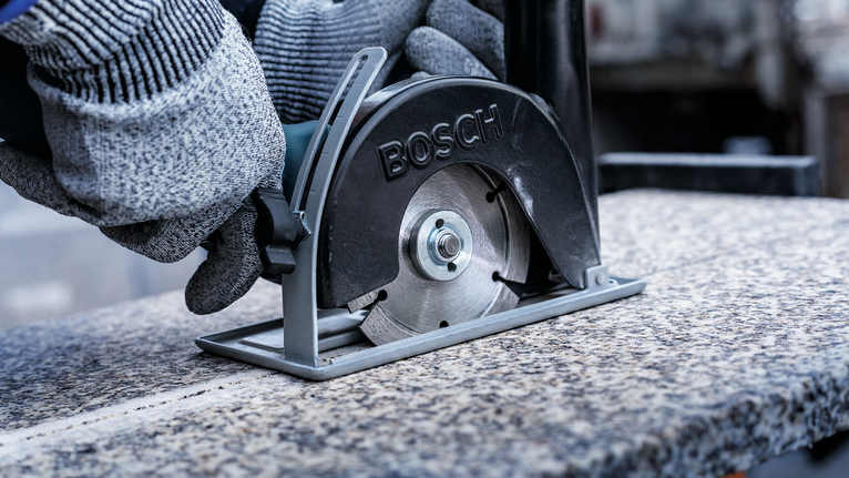 บุคคลที่สวมอุปกรณ์ความปลอดภัยใช้เลื่อยโลหะตัดแผ่นหินแกรนิต