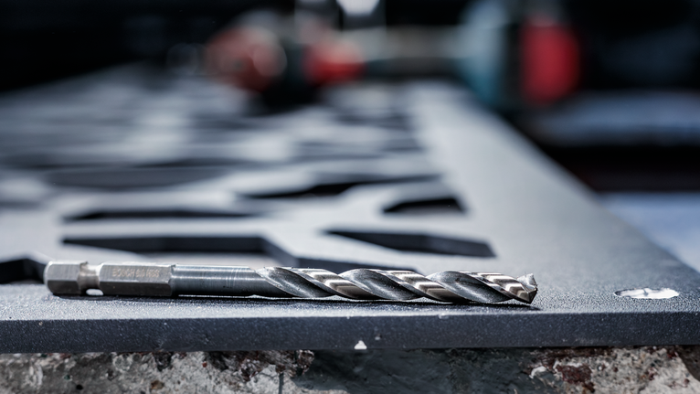ดอกสว่านโลหะวางอยู่บนแผ่นเหล็กที่ตัดแล้วในพื้นที่ทำงานอุตสาหกรรม