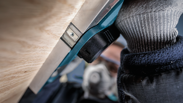 บุคคลที่สวมอุปกรณ์ความปลอดภัยใช้งานเครื่องมือไฟฟ้าใกล้กับพื้นผิวไม้