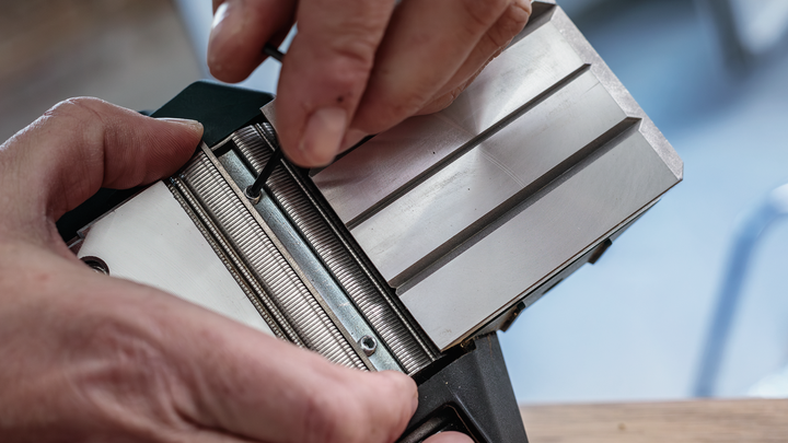 บุคคลกำลังปรับส่วนประกอบเครื่องมือโลหะโดยใช้ประแจหกเหลี่ยม