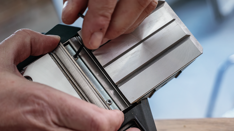 บุคคลกำลังปรับส่วนประกอบเครื่องมือโลหะโดยใช้ประแจหกเหลี่ยม