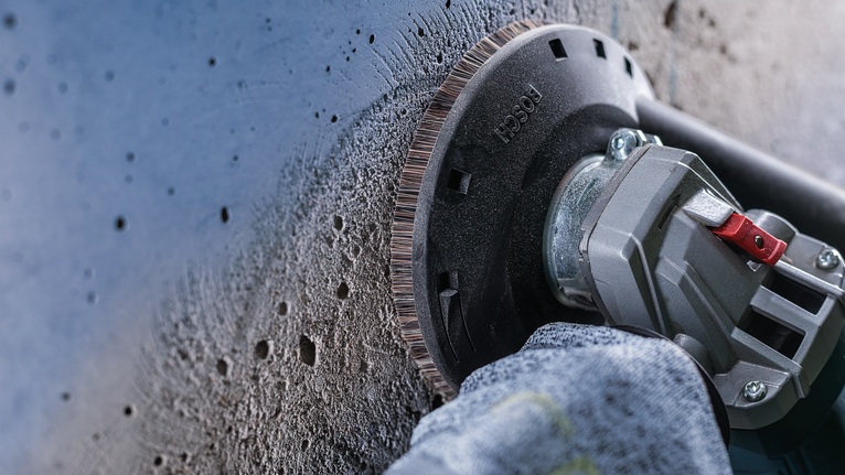 บุคคลที่สวมอุปกรณ์ด้านความปลอดภัยใช้เครื่องเจียรเพื่อขัดผนังคอนกรีต.