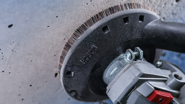 แปรงถ้วยลวดที่ติดอยู่กับเครื่องมือไฟฟ้าใช้ทำความสะอาดพื้นผิวของผนังคอนกรีต.