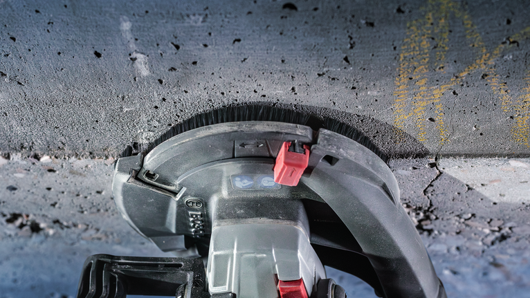 เครื่องมือไฟฟ้าเจียรไปตามพื้นคอนกรีต โดยมองเห็นหัวแปรงปัดฝุ่น
