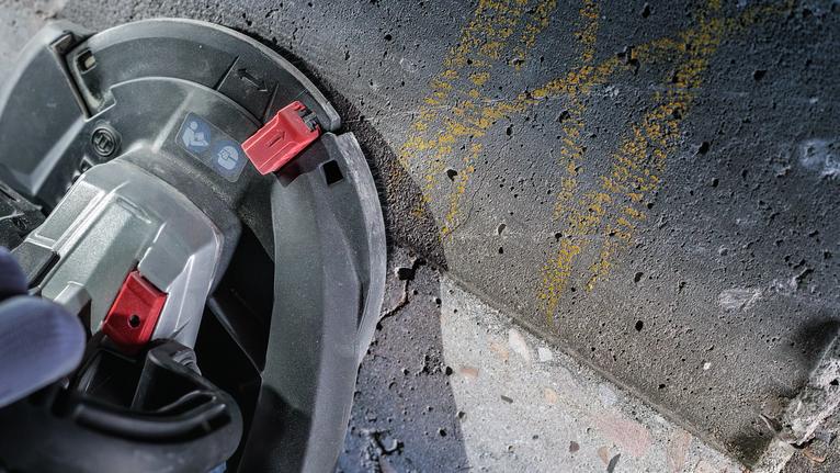 บุคคลที่สวมอุปกรณ์ความปลอดภัยใช้เลื่อยวงเดือนตัดพื้นคอนกรีต