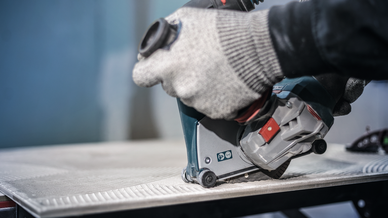 บุคคลที่สวมอุปกรณ์ความปลอดภัยใช้เครื่องมือไฟฟ้าตัดกระเบื้อง