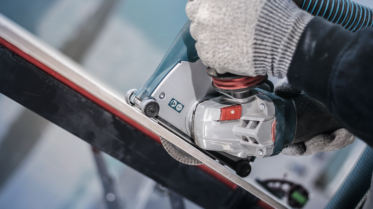 บุคคลที่สวมอุปกรณ์ความปลอดภัยใช้เครื่องมือไฟฟ้าตัดแท่งโลหะ