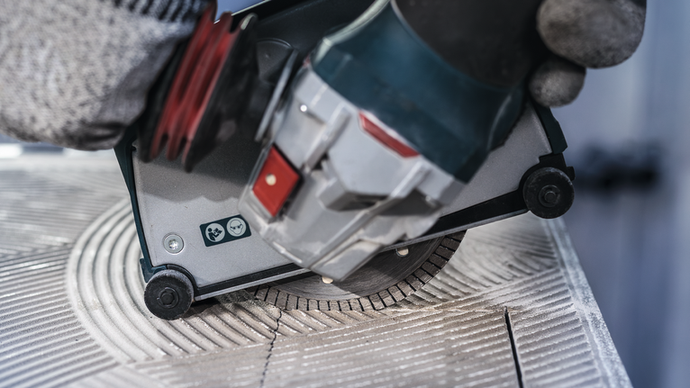 บุคคลที่สวมอุปกรณ์ความปลอดภัยใช้เลื่อยวงเดือนตัดกระเบื้องเซรามิก