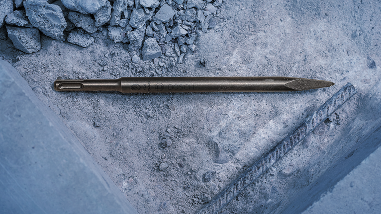 สิ่วแหลมวางอยู่บนเศษคอนกรีตข้างเหล็กเส้นที่โผล่ออกมา