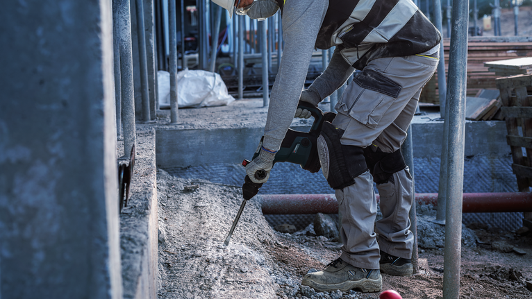 บุคคลที่สวมอุปกรณ์ความปลอดภัยทำลายคอนกรีตในสถานที่ก่อสร้าง