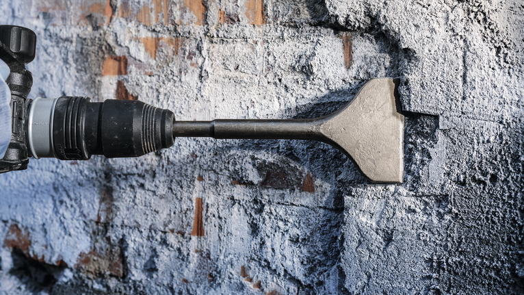 ค้อนสิ่วทุบผนังคอนกรีตในกระบวนการรื้อถอน