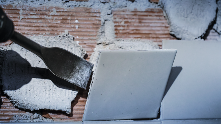 เครื่องมือสิ่วสำหรับขูดเอาแผ่นกระเบื้องผนังออก โดยขจัดฝุ่นและเศษต่างๆ ที่มองเห็นได้บนพื้นผิว.