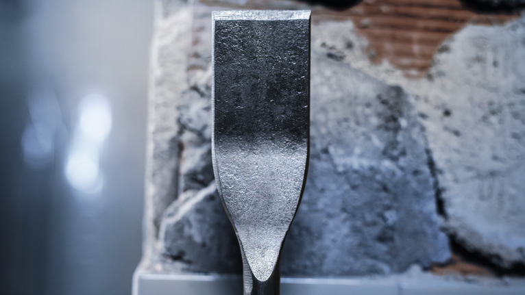 ดอกสกัดวางชิดกับผนังคอนกรีตที่เสียหาย