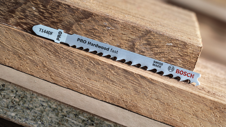 ใบเลื่อยจิ๊กซอว์วางอยู่บนชิ้นไม้เนื้อแข็งที่ซ้อนกัน