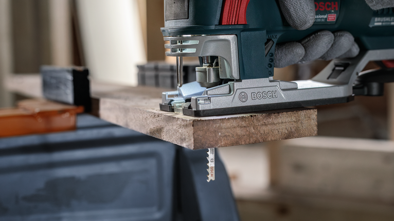 บุคคลที่สวมอุปกรณ์ความปลอดภัยใช้จิ๊กซอว์ตัดแผ่นไม้