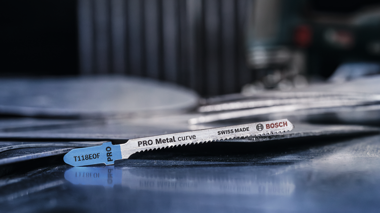 ใบเลื่อยโลหะวางอยู่บนแผ่นโลหะที่วางซ้อนกันในโรงงาน